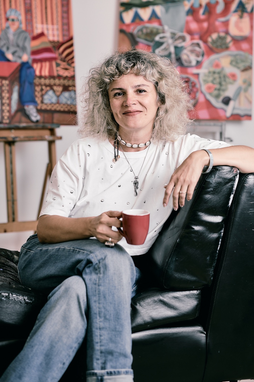 Gülfem Çetin Çapcı in her Berlin studio, with paintings behind her